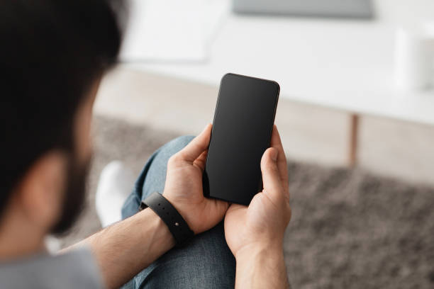 istock Mockup image with man holding cellphone with blank black screen, messaging or surfing internet 1319055840