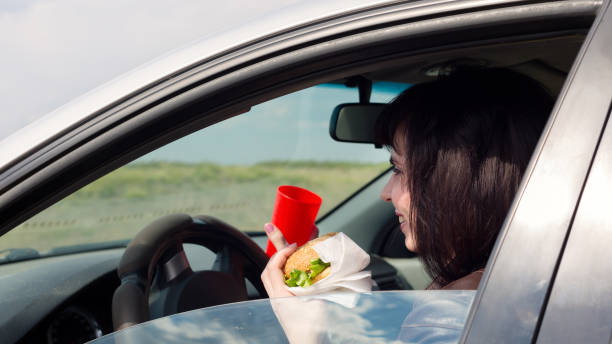 istock Smiling woman in a car driving with a burger 1319057955