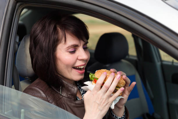 istock Smiling woman in a car driving with a burger 1319057972