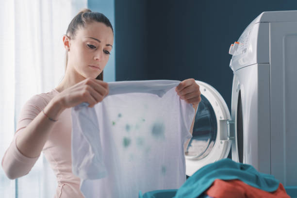 mujer decepcionada sosteniendo ropa manchada - garment emotional stress equipment household equipment fotografías e imágenes de stock
