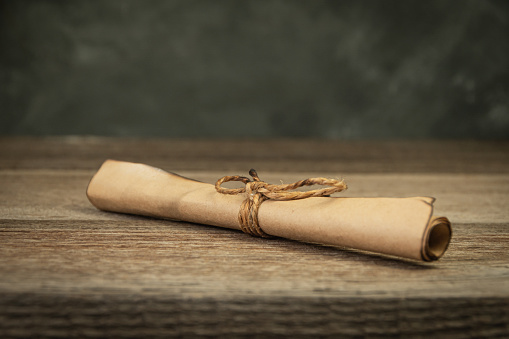Parchment scroll with burnt edges is tied with rope