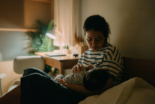 a woman breastfeeding her baby. - baby lying down sleeping asian ethnicity imagens e fotografias de stock