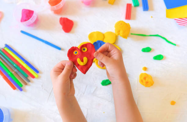 istock Child playing with plasticine, colorful modeling clay and sculpting heart . 1319066682