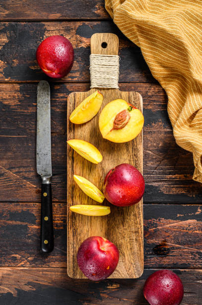 istock Sliced ripe red nectarines on a chopping Board. Dark Wooden background. Top view 1319067230