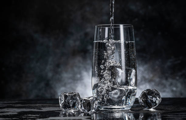 verter agua de la botella en vidrio sobre fondo negro - water flowing water pouring ice fotografías e imágenes de stock