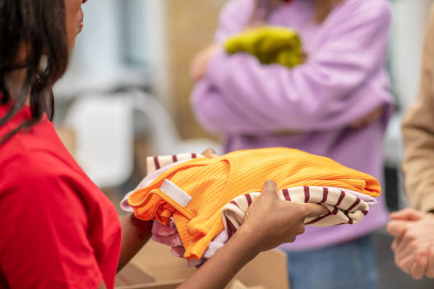 Dark-skinned volunteer girl holding offering clothes