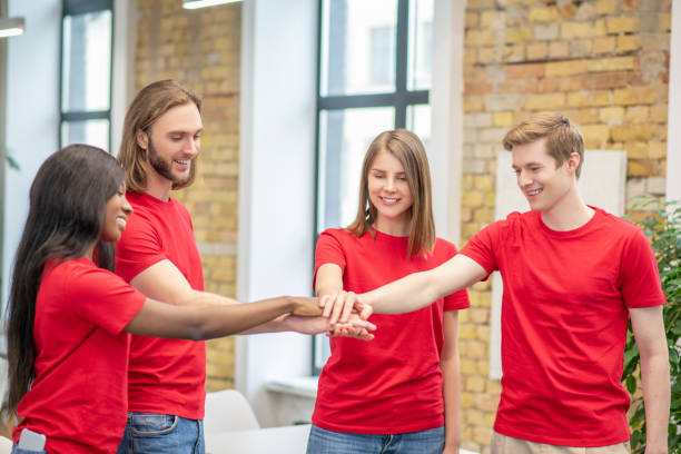 istock Joyful young volunteers showing togetherness gesture 1319072180