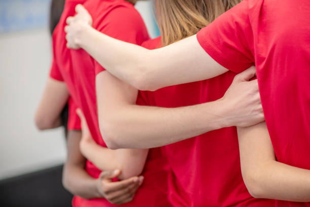 Hands hugging back of volunteer in red tshirt Support, union. Friendly hands hugging the backs of volunteers in red tshirt, faces are not visible initiative photos stock pictures, royalty-free photos & images
