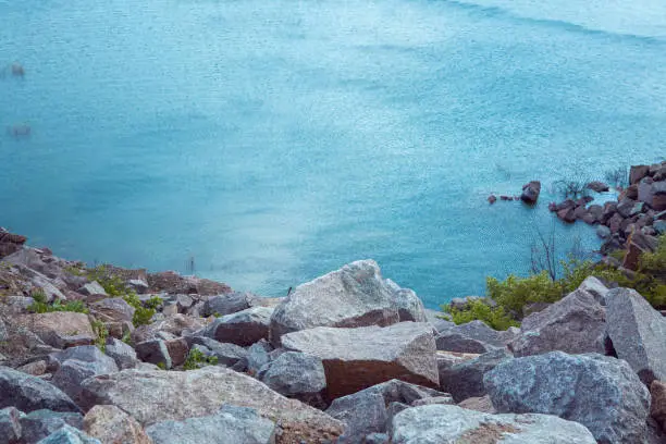 Beautiful coast of the Kamenka river in spring. Colorful landscape with lake, stones and grass, blue sky with white clouds reflected in the water. Nature. Vivid landscapes.