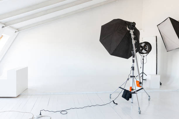 istock Empty photo studio with lighting equipment. Photographer workplace interior with professional tool set gear. Flash light white background scenes ready for studio shooting. Modern photographer studio 1319074882