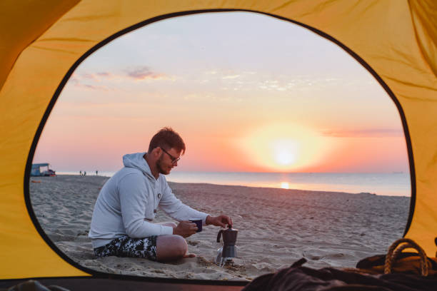 istock man cooking coffee at sea sandy beach. summer camping vacation 1319075623