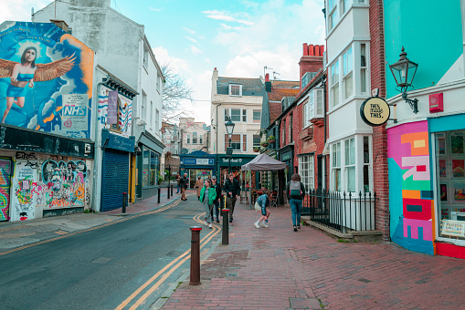 Brighton, UK - 17 May, 2021: the quaint shops and streets of the lanes of Brighton, UK. The sides of buildings are covered with murals and colorful street art.