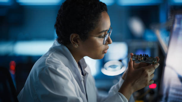 istock Modern Electronics Research and Development Facility: Beautiful Black Female Engineer Inspects Printed Circuit Board Motherboard. Scientist Designs Industrial PCB, Silicon Microchips, Semiconductors 1319077872