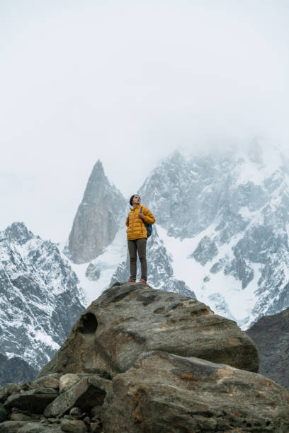 femme restant sur la roche sur l’arrière-plan du pic enneigé de bublimotin dans le nord du pakistan - climbing mountain climbing rock climbing women photos et images de collection