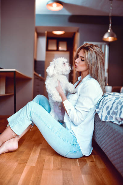 istock Small Puppy Getting Kiss From Female Owner While Spending Day Together On Bedroom Floor 1319083721