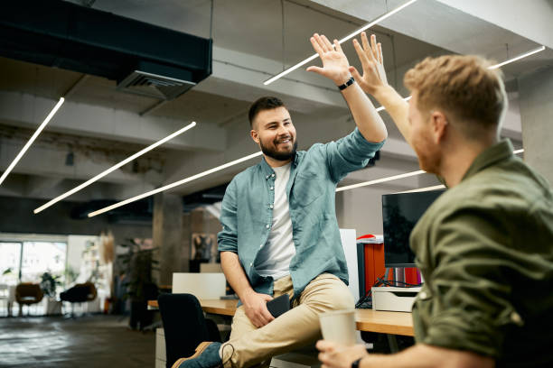 glückliche kreative geschäftskollegen geben sich während der arbeit im büro high-five. - high five stock-fotos und bilder