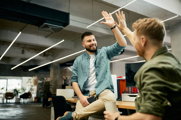 collègues d’affaires créatifs heureux donnant high-five à l’autre tout en travaillant dans le bureau. - tope là photos et images de collection