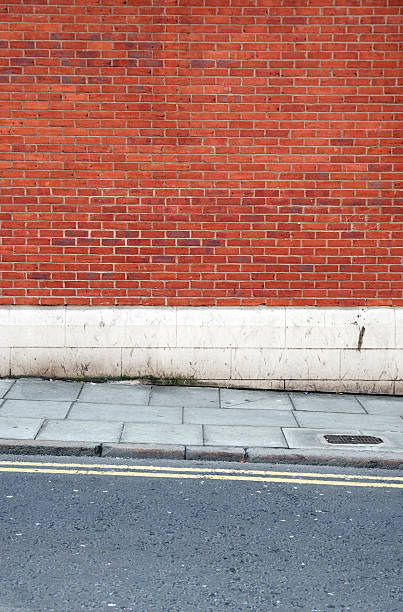 istock Urban background UK - Red brick wall with sidewalk 131908378