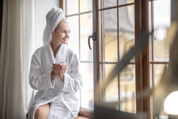 istock A woman in a white robe sitting near the window and having tea 1319084959