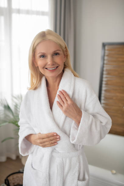 istock Blonde woman in a white bath robe looking contented 1319085024