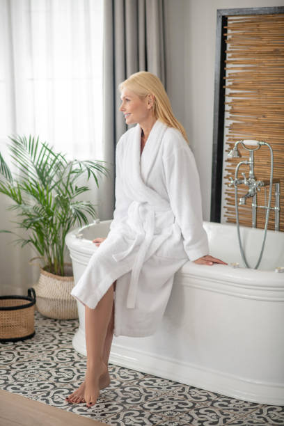istock Blonde woman in a white bath robe looking contented 1319085034