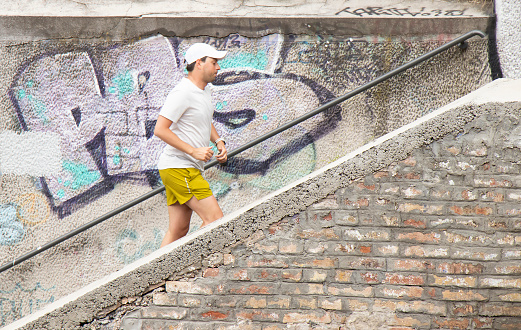 Belgrade, Serbia - May 14, 2021: One young man jogging alone and running up outdoor city stairs on a sunny day