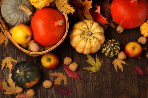 istock Dried leaves, pumpkins, apples, nuts and cinnamons on dark rustic wooden background. 1319085672
