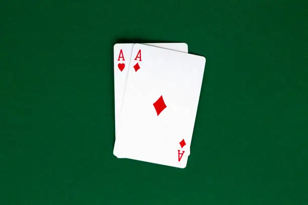 Photo of two red aces. playing cards with blue deck on the green table. combination of cards on a green casino desk background. top view. poker