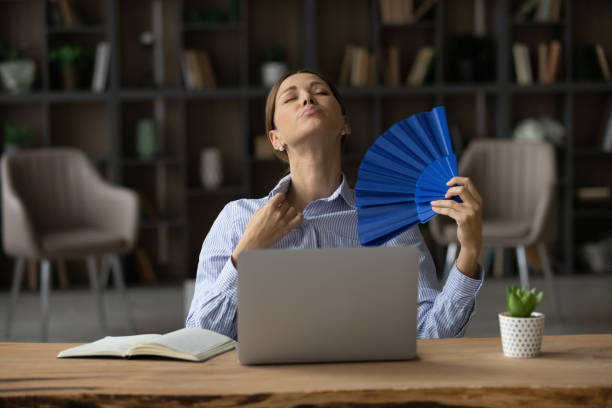 jovem senta-se ao laptop em hot office usar ventilador - office fan - fotografias e filmes do acervo