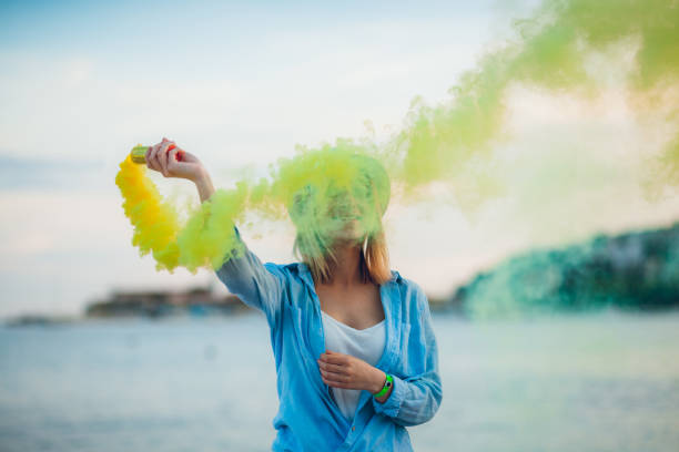 istock Woman having fun with smoke bomb on the beach 1319087995