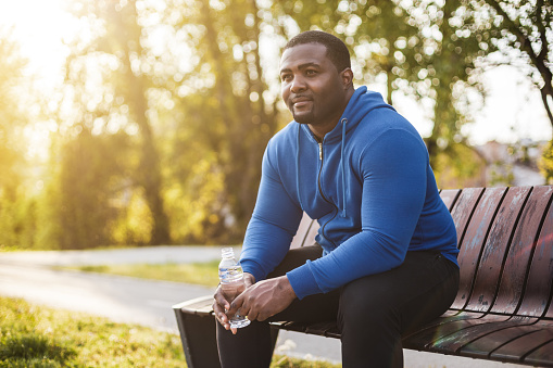 Man resting on bench after exercise and  drinking water .