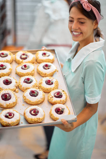 istock A beautiful retro looking young girl holding a tray with delicious donuts in a candy workshop. Pastry, dessert, sweet, making 1319088645