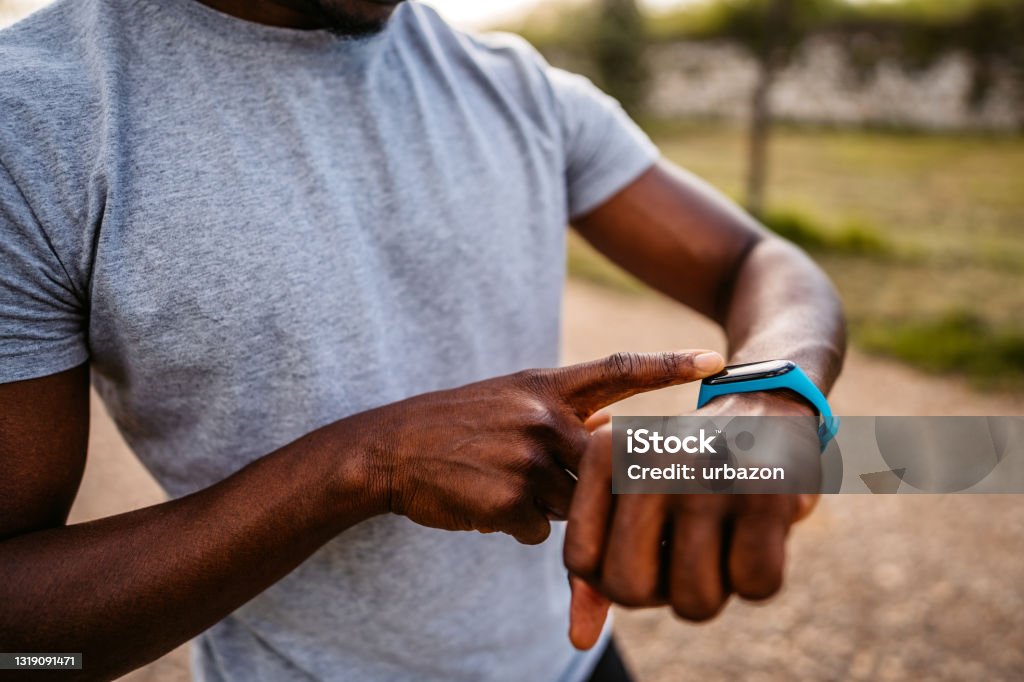 Athlete check fitness tracker after training in nature Athlete check fitness tracker on smartwatch or playing his music playlist after training in nature. Fitness Tracker Stock Photo