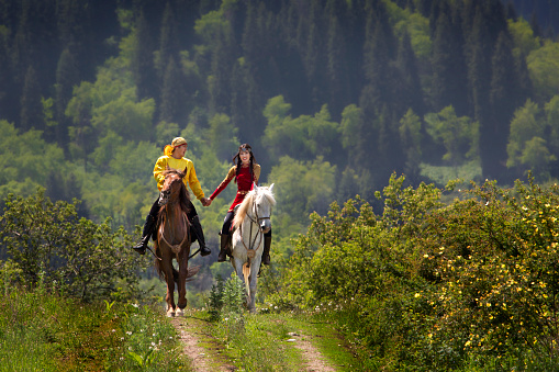 Almaty, Kazakhstan - June 6, 2018: Kazakh couple in national costumes hand in hand on their horse in Almaty, Kazakhstan.