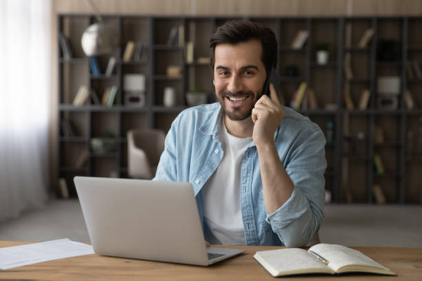 istock Head shot portrait smiling businessman talking on phone, using laptop 1319095468