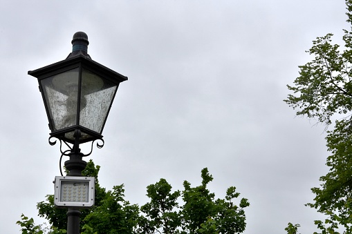 Historic street lantern and LED diode reflector for illumination of public places. Two types of illumination technologies, retro and modern one are placed together. Low angle view with copy space.