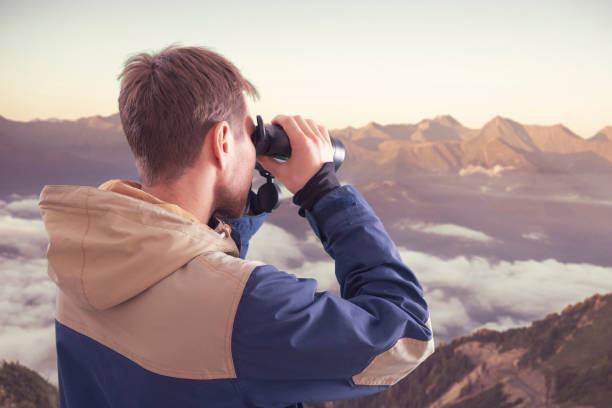 istock young person hiking in the mountains and using binoculars, travel concept 1319101914