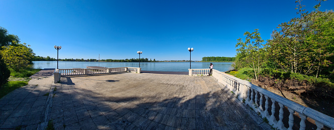 Snagov, Romania - May 9, 2021: Panorama with a woman on the Snagov Palace pier at the Snagov lake.