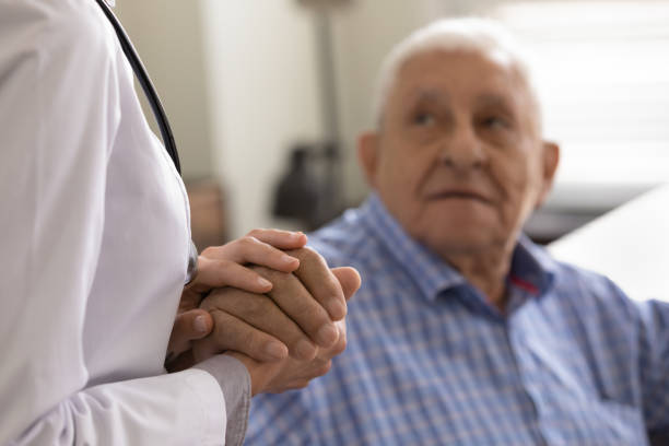 Compassionate female doctor nurse supporting consoling aged retired man patient Helping hands. Close up of kind compassionate female doctor nurse in white coat supporting soothing consoling aged retired man patient. Focus on sick old man palm in hands of medical worker caregiver alzheimer's disease stock pictures, royalty-free photos & images