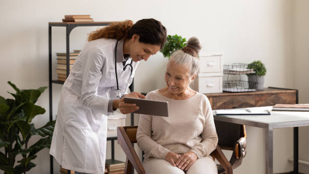 istock Young female doctor consult aged lady patient using digital tablet 1319103355