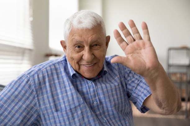istock Happy smiling elderly man looking at camera waving hand hi 1319103369