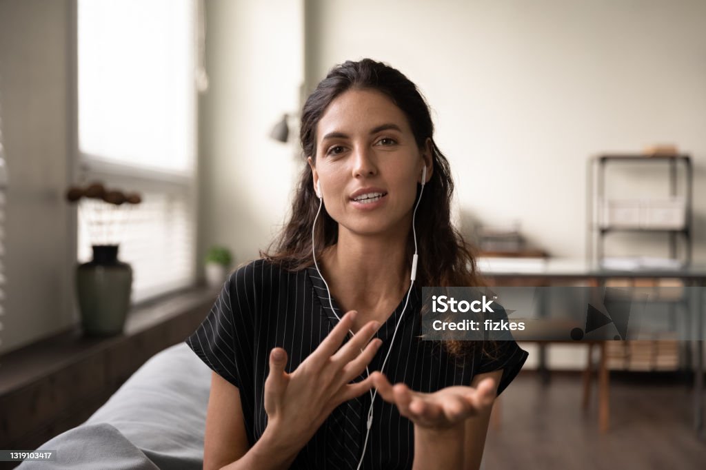 Inspired female teacher in headphones meet students online give class Video conversation. Inspired latin female teacher in headphones meet students online look at camera give virtual class. Portrait of confident young saleswoman wear headset consult client by videocall Video Call Stock Photo