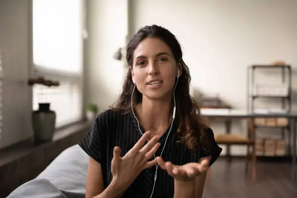 Video conversation. Inspired latin female teacher in headphones meet students online look at camera give virtual class. Portrait of confident young saleswoman wear headset consult client by videocall