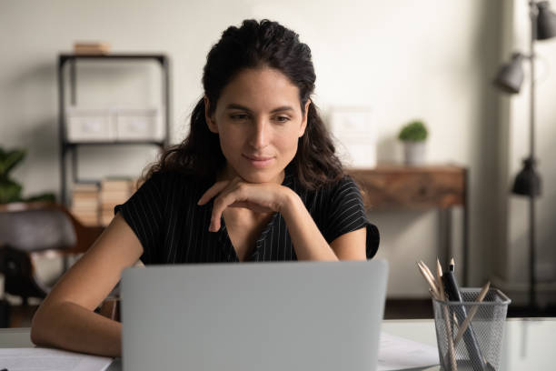 Young lady office worker doing interesting job on laptop online Good work. Smiling positive young lady office worker doing interesting job online reading pleasant email on laptop screen. Happy millennial latin woman sit by laptop at workplace enjoy working process israeli ethnicity stock pictures, royalty-free photos & images