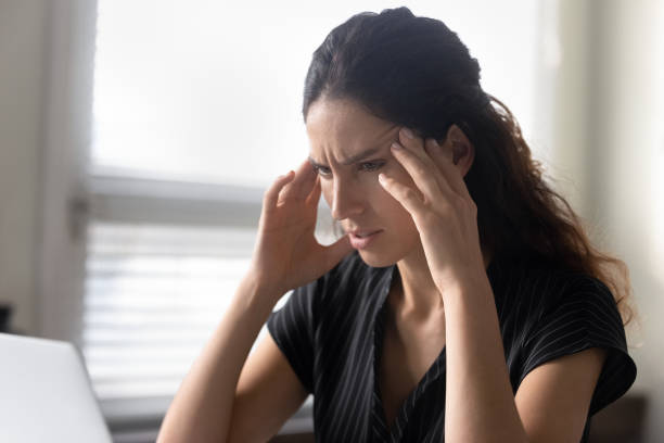 Stressed young latina woman sit by pc feel information overload What should I do. Stressed latina woman sit by pc rub temples feel information overload unable to focus attention on work. Anxious young female try to remember important thing solve unexpected problem information overload photos stock pictures, royalty-free photos & images