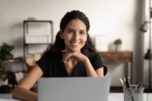 istock Confident young latin female posing by office computer at desk 1319103436