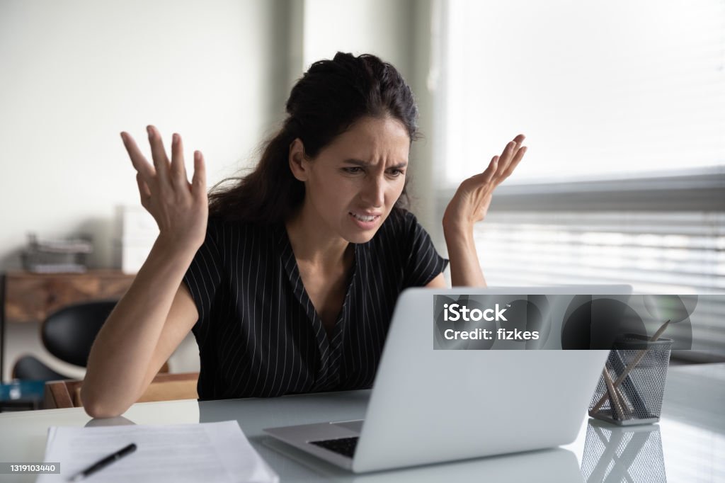 Mad young woman worker losing job result on broken pc What is wrong. Anxious angry hispanic female splash hands unable to access database on laptop forgetting password having weak wifi signal. Mad shocked young woman worker losing job result on broken pc Frustration Stock Photo