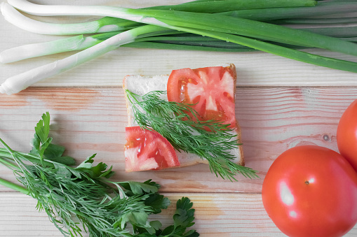Sandwich with tomatoes and herbs, on a wooden background, close-up