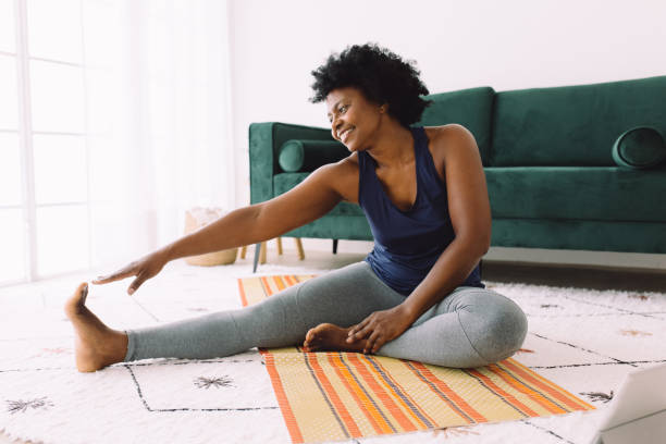 african woman doing stretching at home - esticar imagens e fotografias de stock