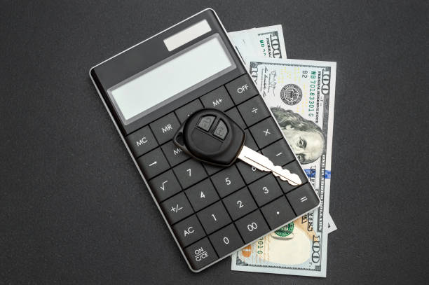 istock Car key with calculator and money on black background. 1319109911